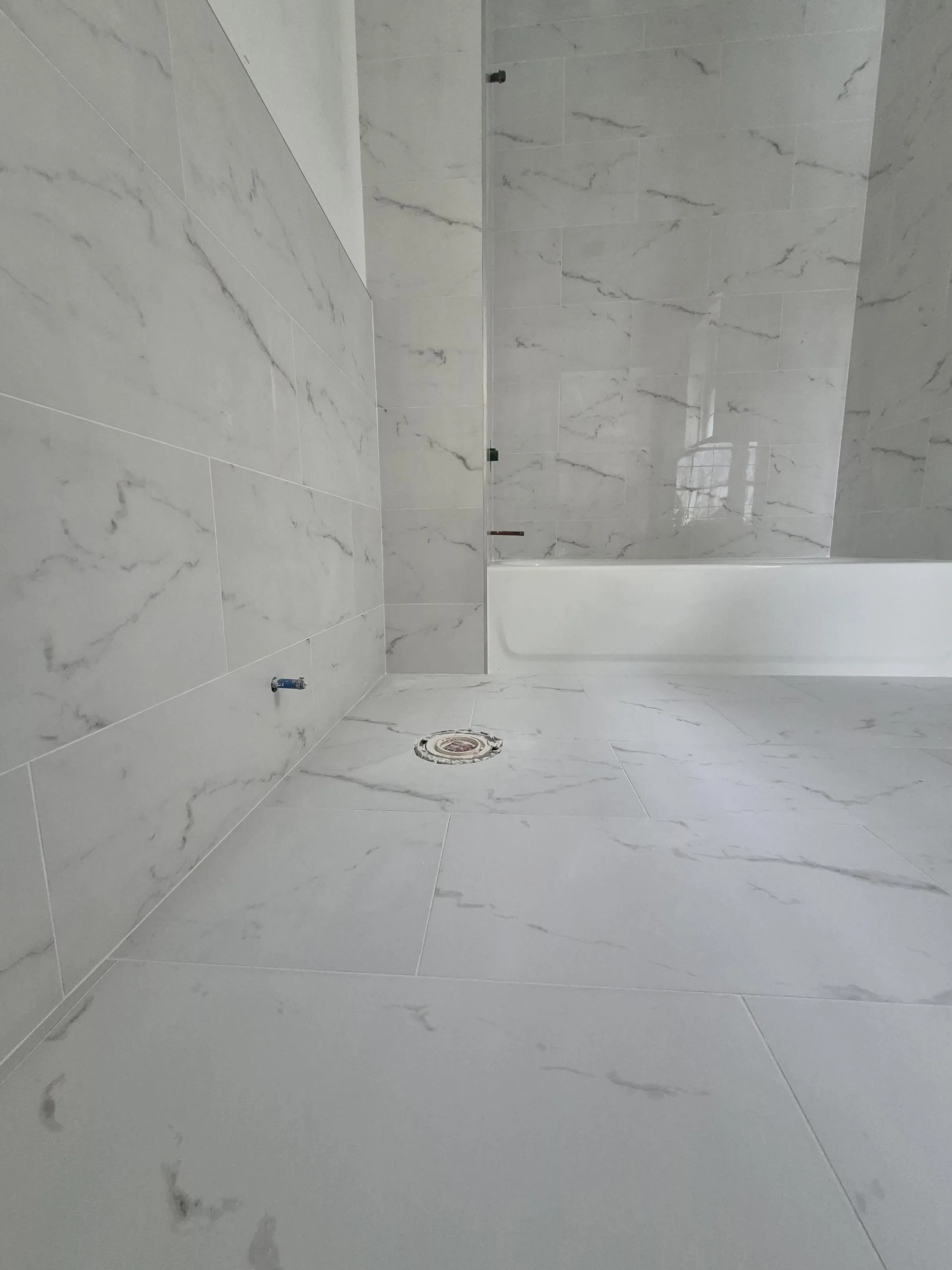 Walk-in marble bathroom with mitred outside-corner returns — reference for high-end natural-stone tile finish