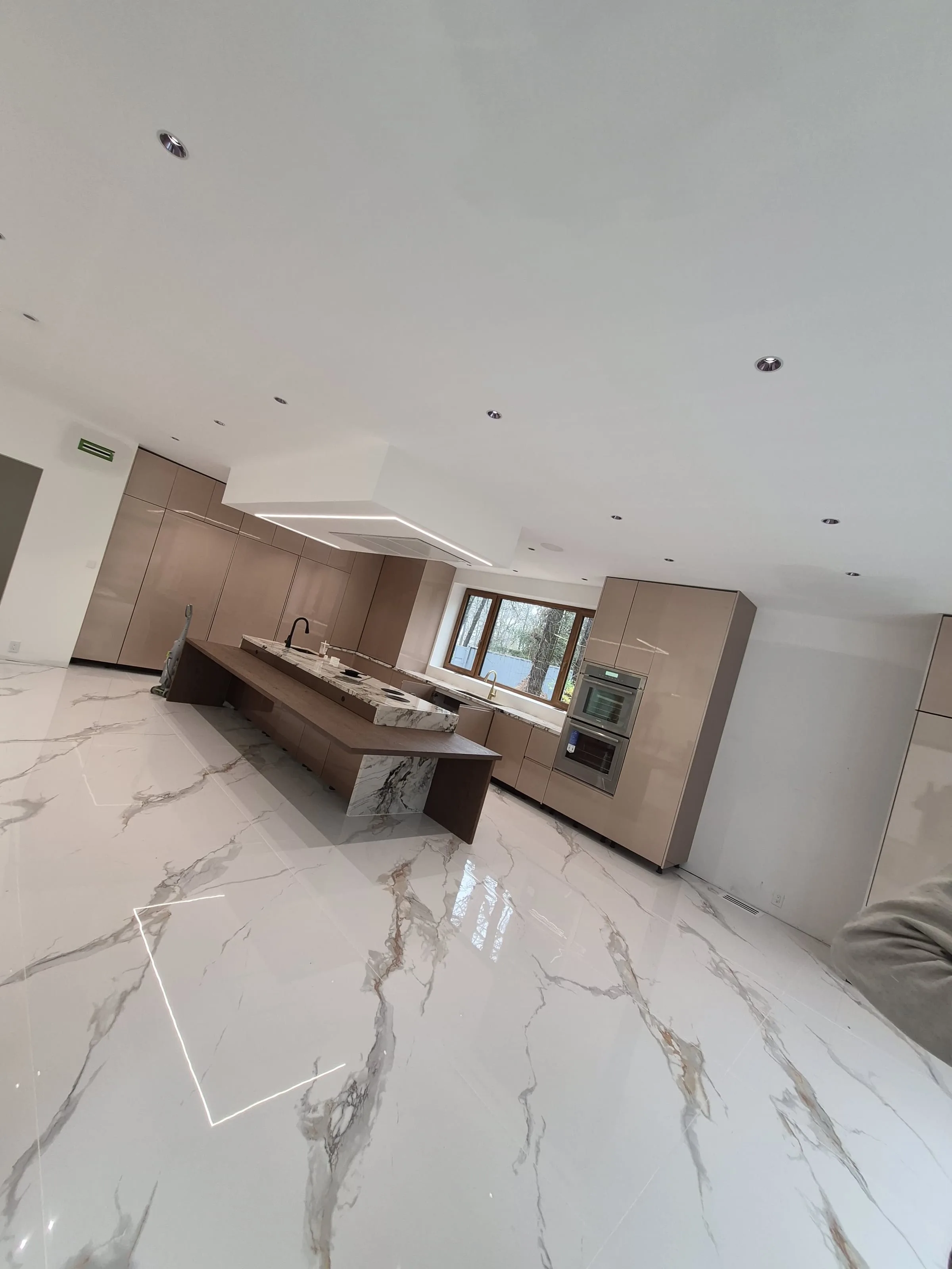 Modern kitchen with marble waterfall island and continuous slab-style backsplash — reference for kitchen tile and slab-backsplash work